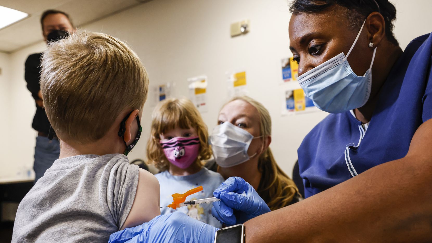 Registered nurse Barbara Davis administers a COVID-19 vaccine to Robert Holt, 5, as his...