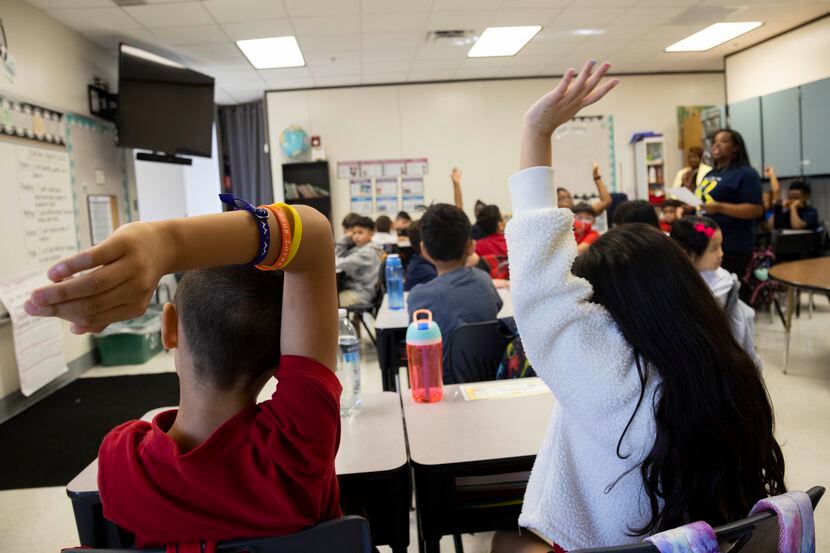 Students raise their hands as third grade teacher Anjelica Turner teaches about character...