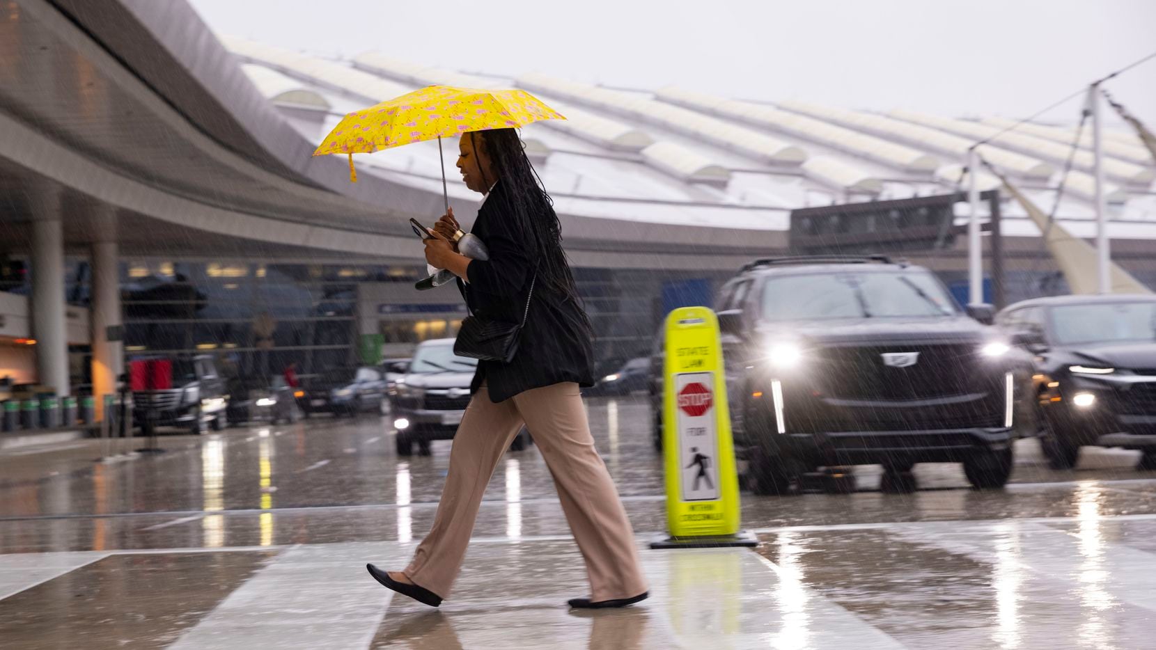 Alexis Alexander crosses the street in the rain to go to work at the Grand Hyatt on Friday,...