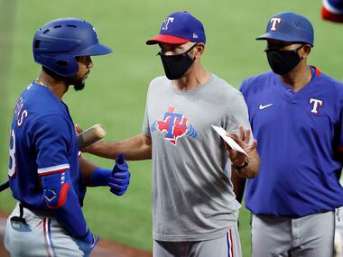 Texas Rangers manager Chris Woodward (middle) wears a mask as he visits with outfielder Leody Taveras during a simulated Summer Camp game inside Globe Life Field in Arlington, Texas, Thursday, July 9, 2020.