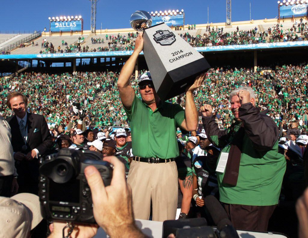 University of North Texas head coach Dan McCarney lifts up the Heart of Dallas Bowl trophy...