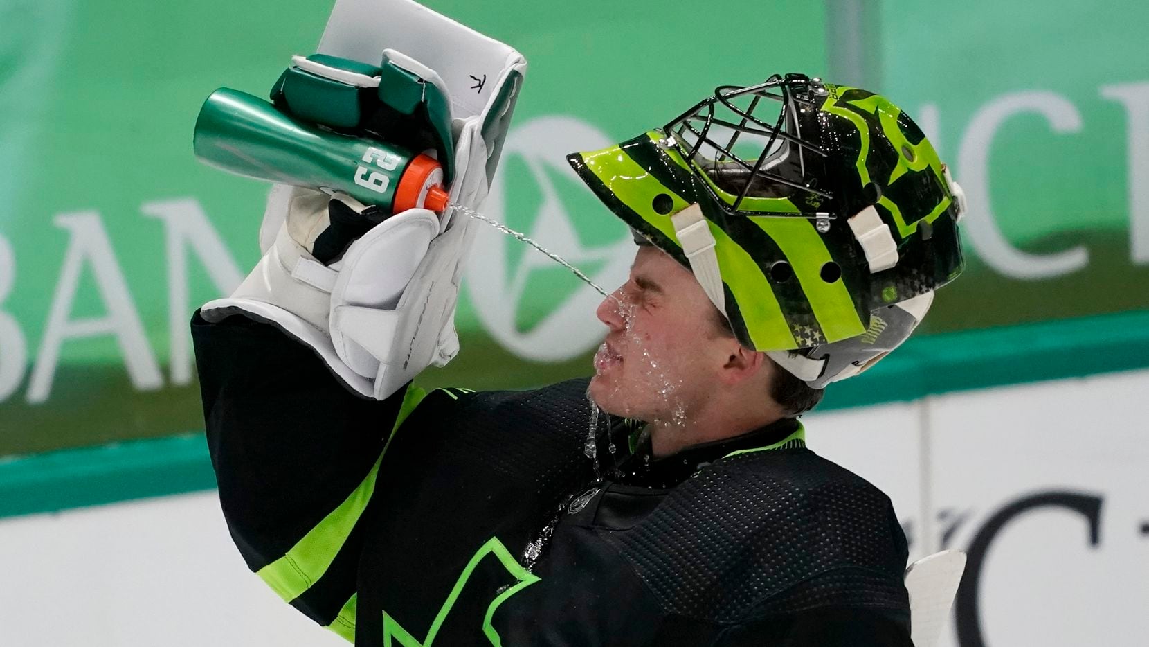 Dallas Stars' Jake Oettinger splashes his face with a drink during a timeout in the second...