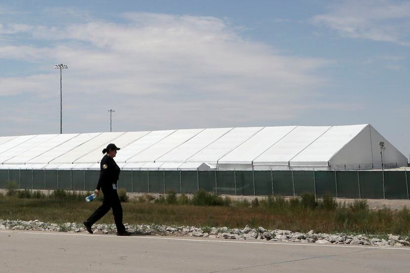 Un guardia de seguridad camina frente a una de las carpas instaladas en El Paso para...