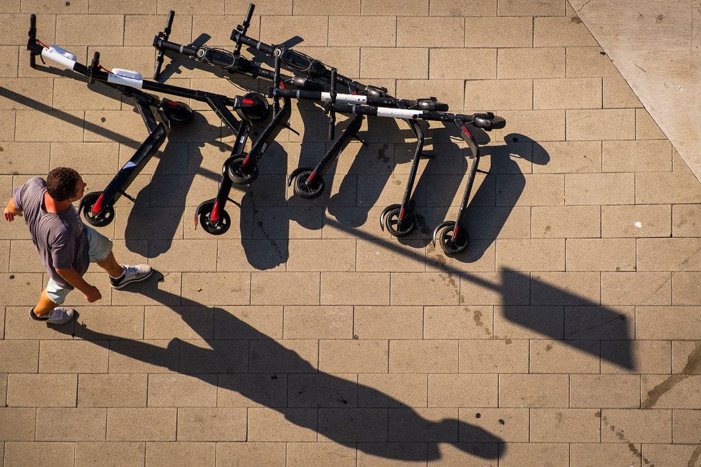 A man walks past a pile of Bird rental scooters lying on Commerce Street in downtown Dallas...