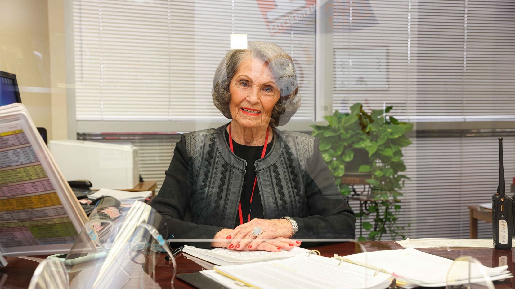 Flo Judd poses behind a plexiglass at her office in Duncanville on Friday, January 29, 2021. Judd, 81-year-old associate principal at Duncanville High School, is in her 50th year in education. Like nearly all K-12 educators in Texas, she's working on campus every day, but she hasn't been able to find a coronavirus vaccine, despite signing up with multiple counties around the Dallas area. (Lola Gomez/The Dallas Morning News)