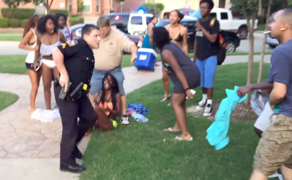 McKinney police officer Eric Casebolt pulls his gun as he turns away from a girl he was...