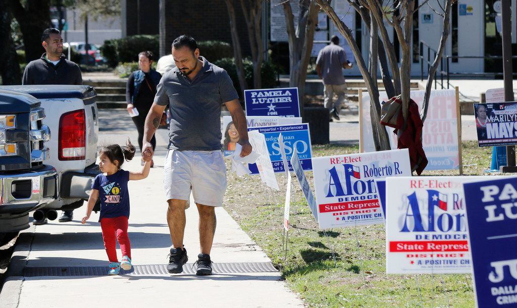 Armando Vergara walks his daughter Evylin, 3, past the Dallas County Government Center,...