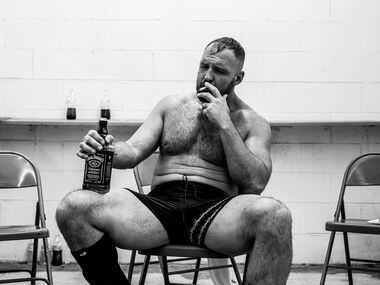 Jon Moxley smokes a cigarette while holding a bottle of Jack Daniels following his match at...