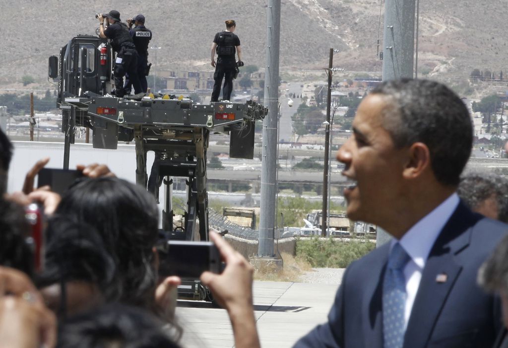 Security personnel scan the horizon as President Barack Obama greets well wishers after...