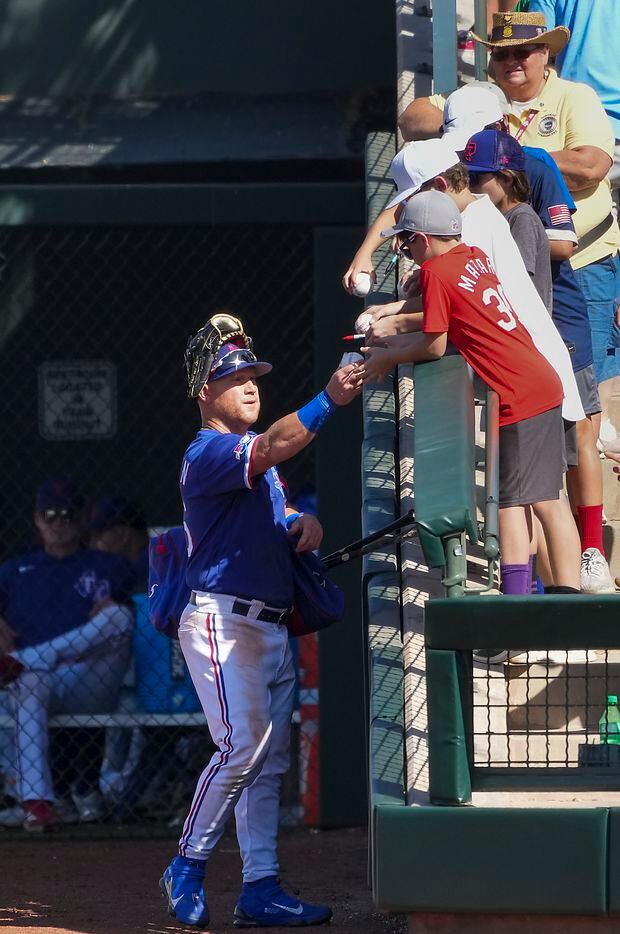 Texas Rangers outfielder Kole Calhoun signs autographs during the sixth inning of a spring...