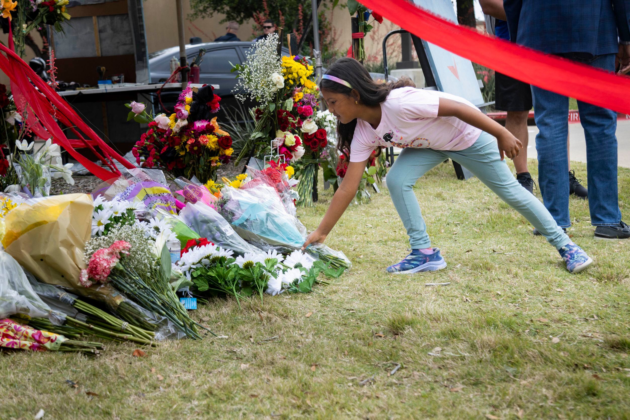 Medha Shamasunder, 7, leaves a bouquet of flowers at the memorial outside the mall honoring...