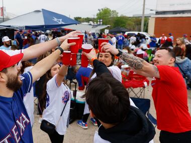 Fans including Colby Phillips (left) of Plano, cheer a drink as they tailgate before the...