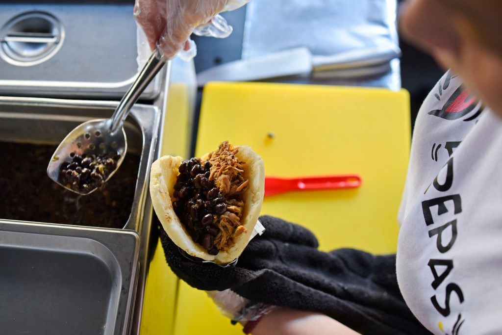 Pamela Lozano, 34, places black beans inside an arepa at her food booth Arepa Nation at the...