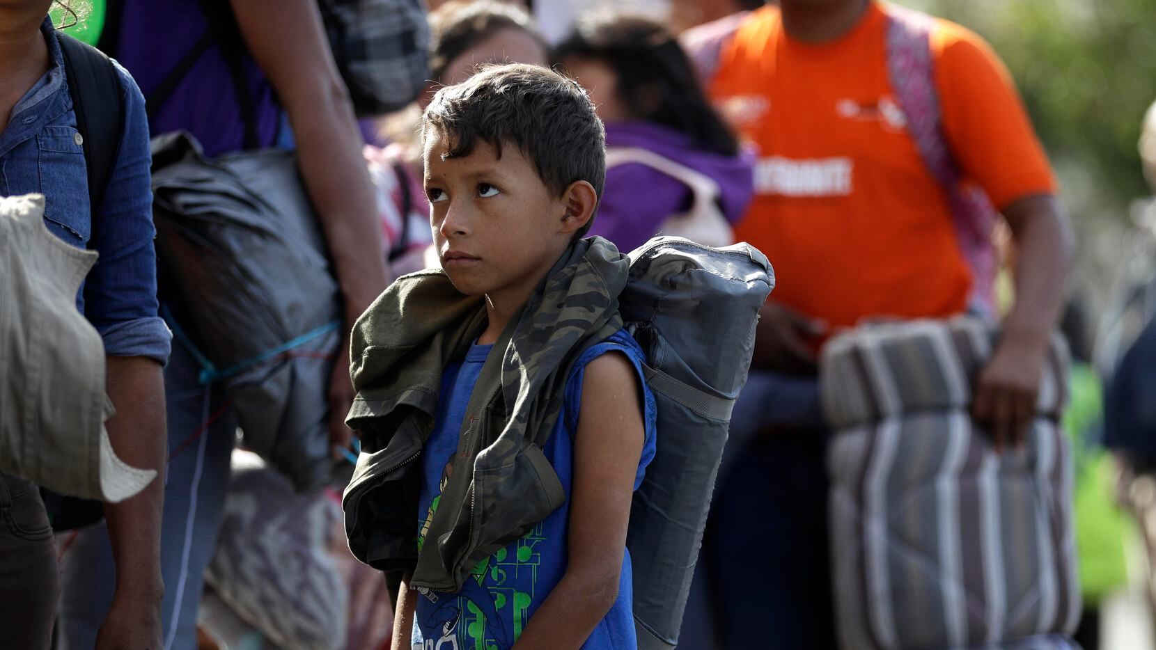 Daniel Gamez, un niño hondureño, hace fila junto a su familia en espera de alimentos en...