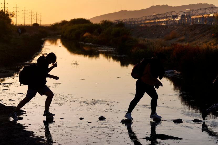 A migrant group coming from Mexico steps across stones in the Rio Grande to get to the U.S....