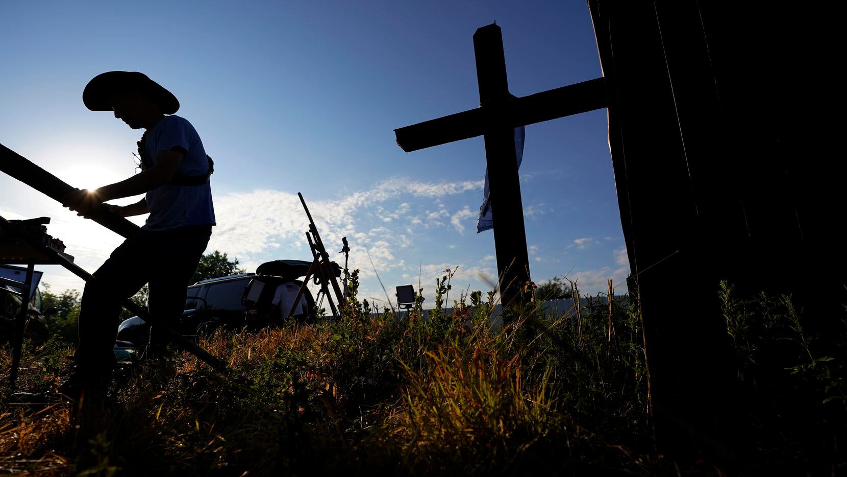 Roberto Marquez of Dallas builds and adds crosses to a make-shift memorial at the site where...