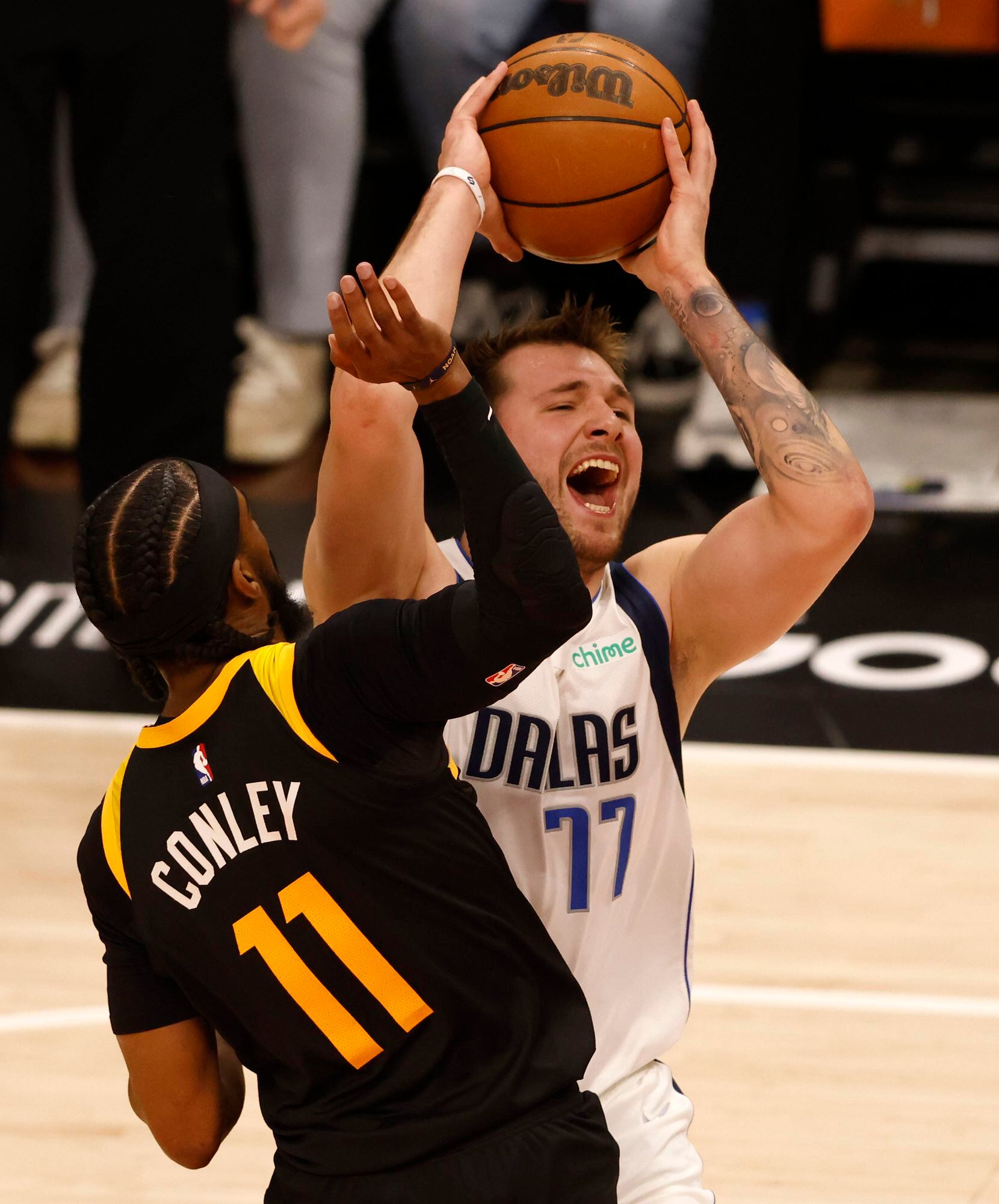 Dallas Mavericks guard Luka Doncic (77) yells as he attempts a shot in front of Utah Jazz...