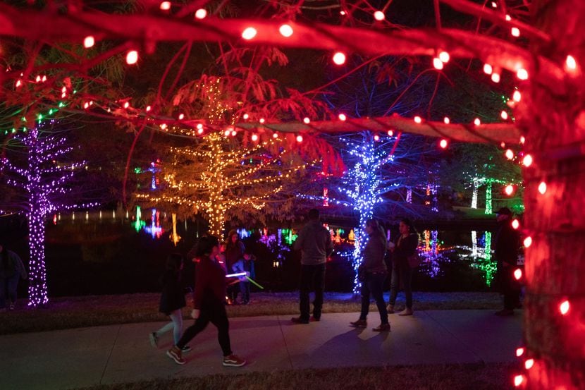 Familias recorren el espectáculo nocturno Vitruvian Lights en Addison. El parque cuenta con...