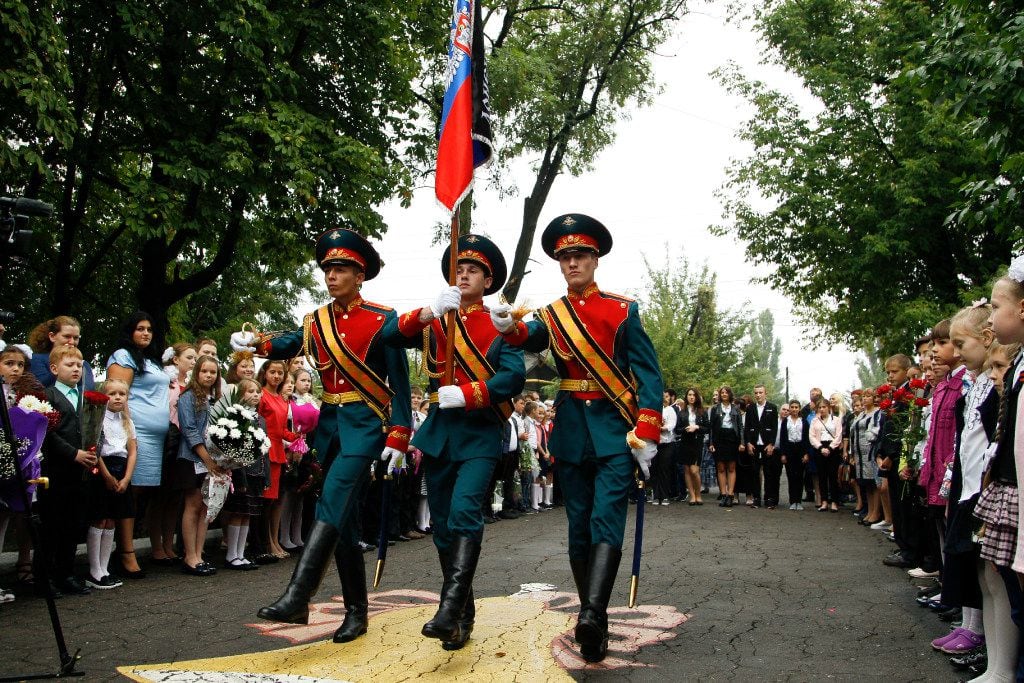 Schoolchildren watch as servicemen carry a flag of the Russia-backed self-proclaimed...