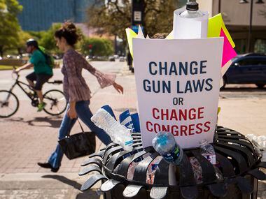 Protest signs and water bottles fill a sidewalk trash bin after a rally and march in support of gun safety laws.