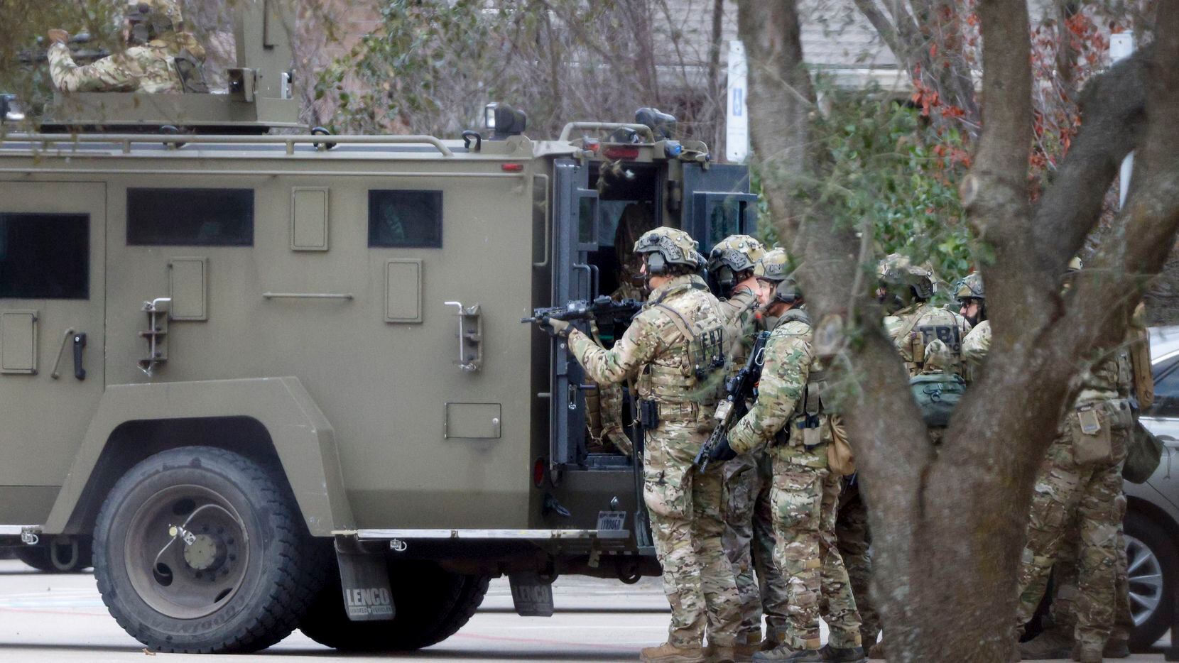 A law-enforcement team stages behind an armored vehicle outside Congregation Beth Israel in...
