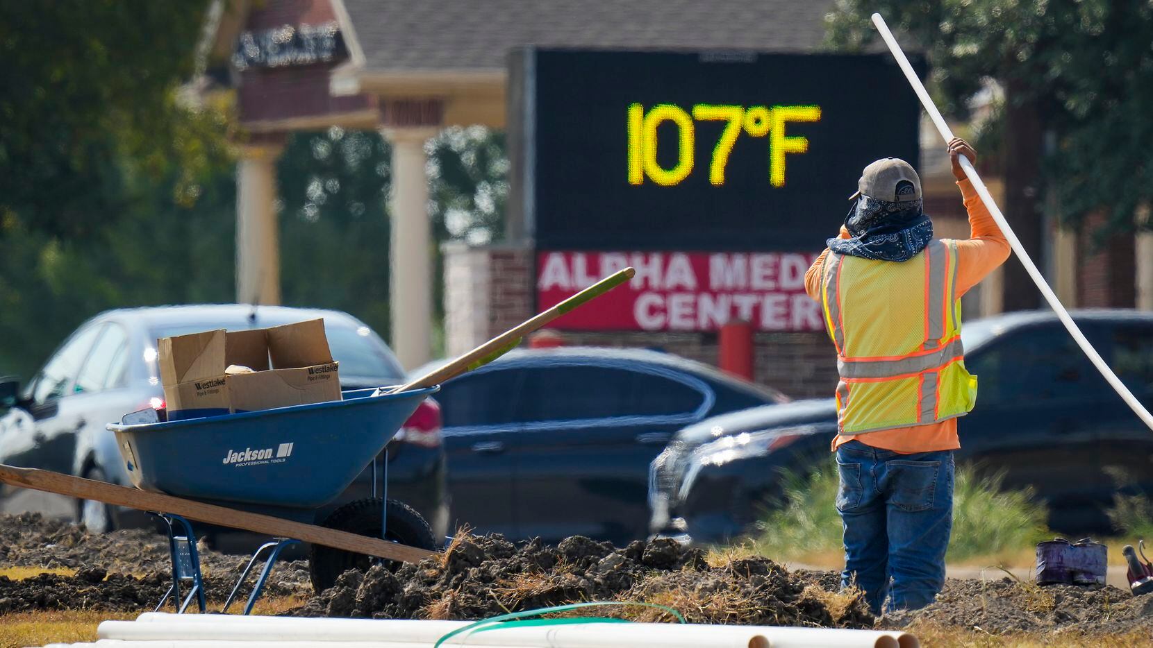 The sign on a business reads 107° as Diego Cardenas works on a construction project in the...