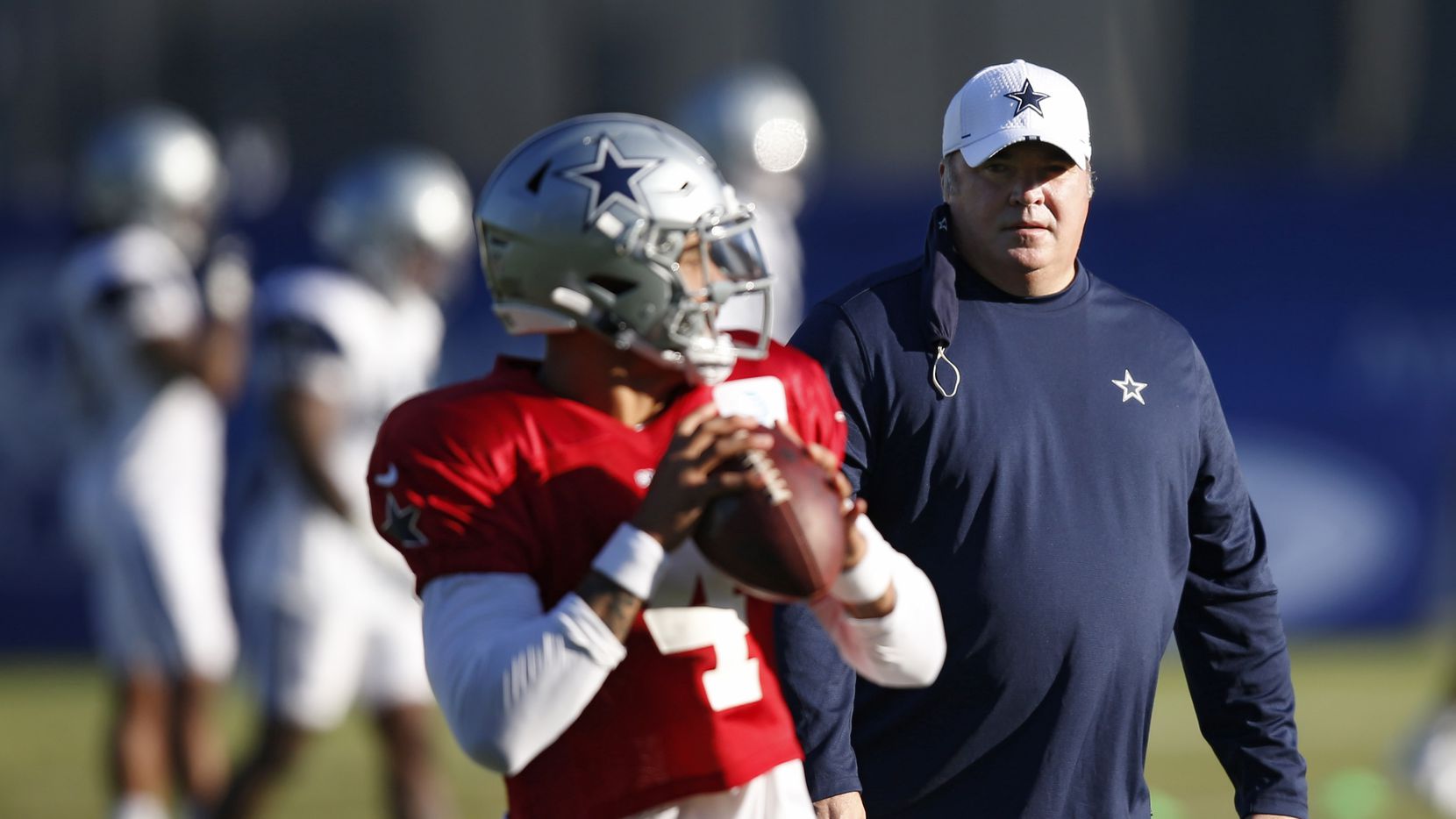 Cowboys head coach Mike McCarthy watches while quarterback Dak Prescott (4) runs through a...