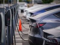A group of Tesla cars line up at charging stations at a dealership in Littleton, Colo., Aug....