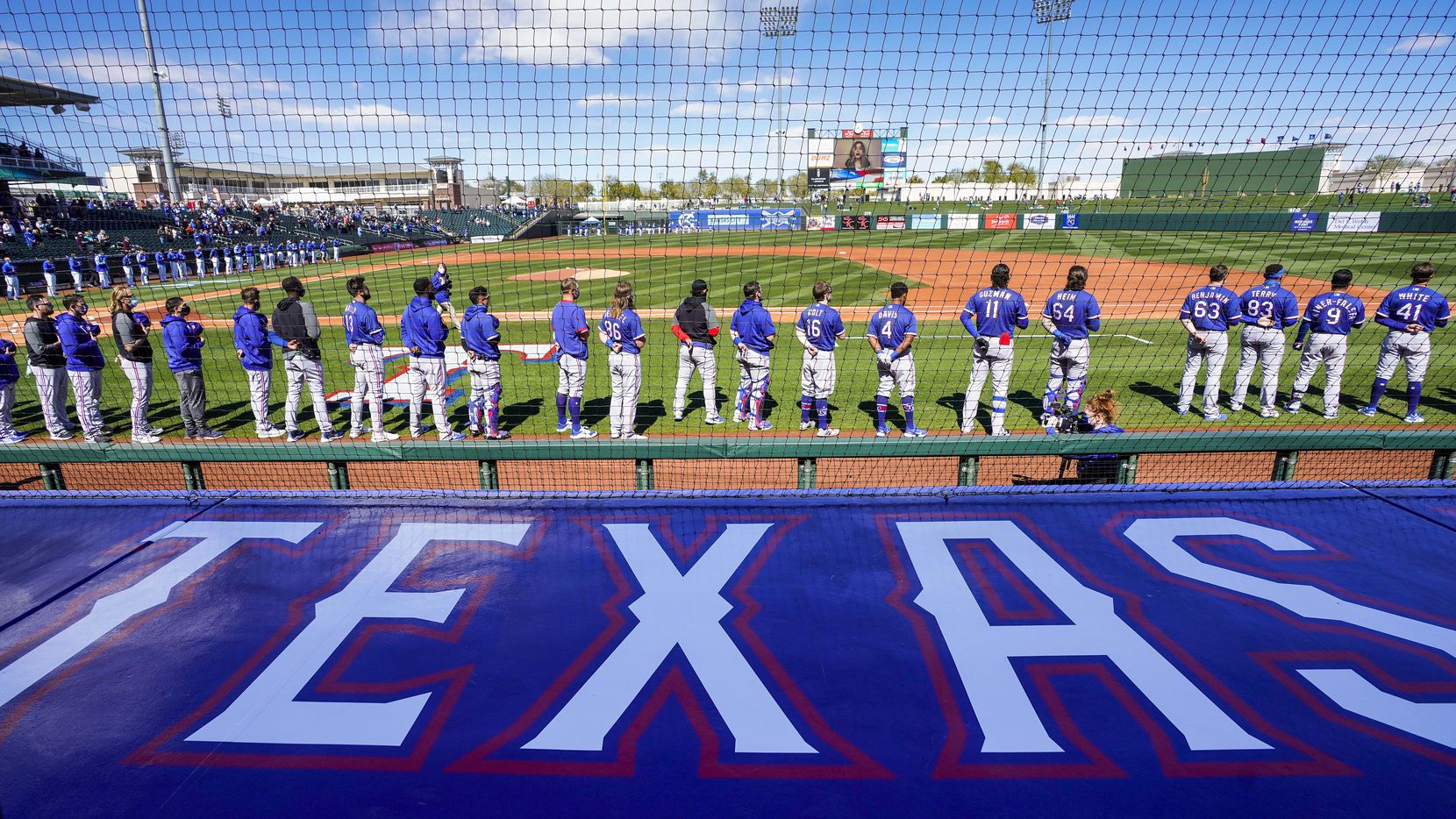 Texas Rangers players stand for the national anthem before a spring training game against...