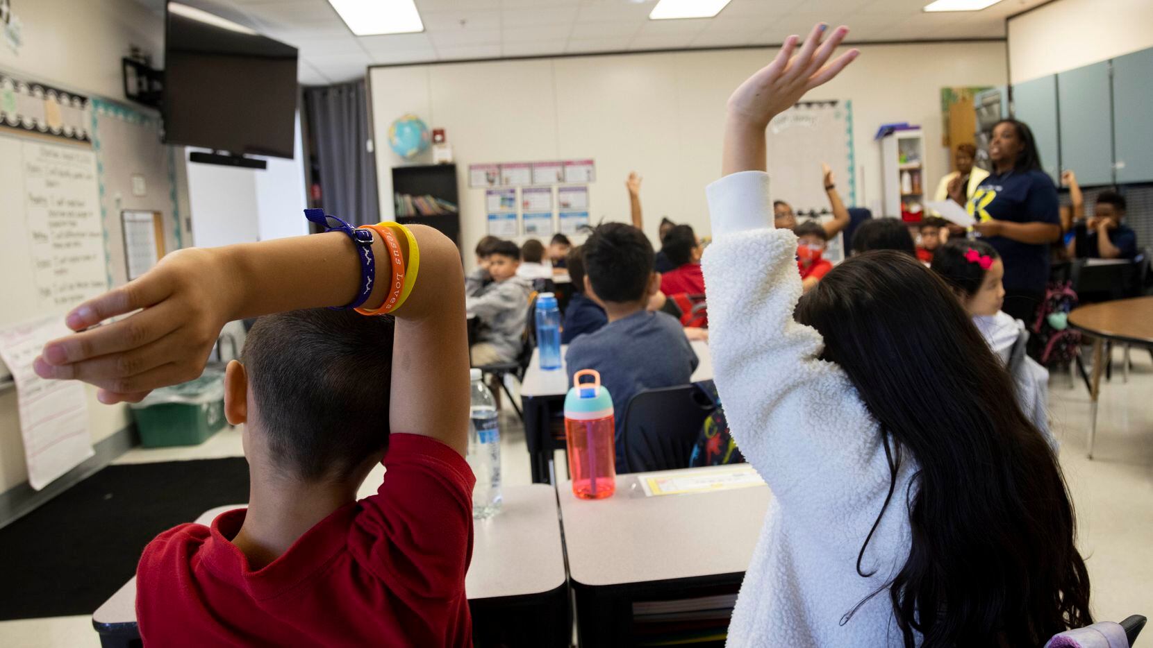 Students raise their hands as third grade teacher Anjelica Turner teaches about character...