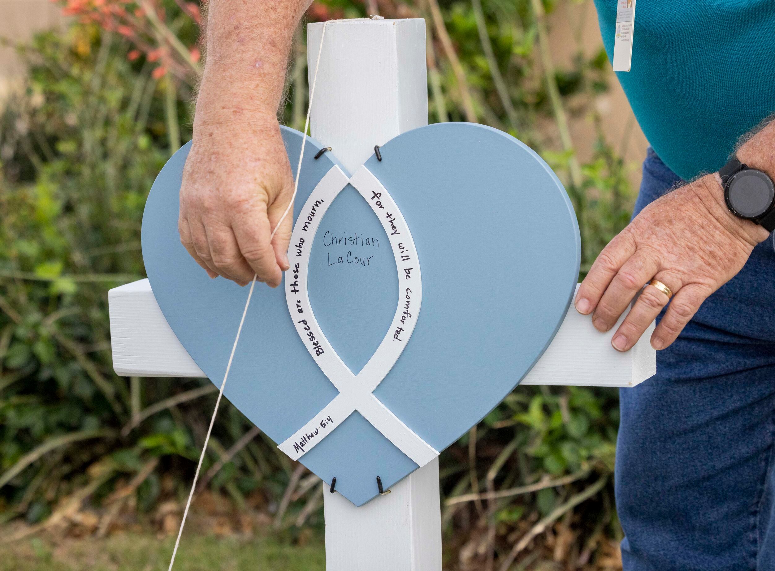 Eddie Carlton, a volunteer with Lutheran Church Charities, places a cross for Christian...