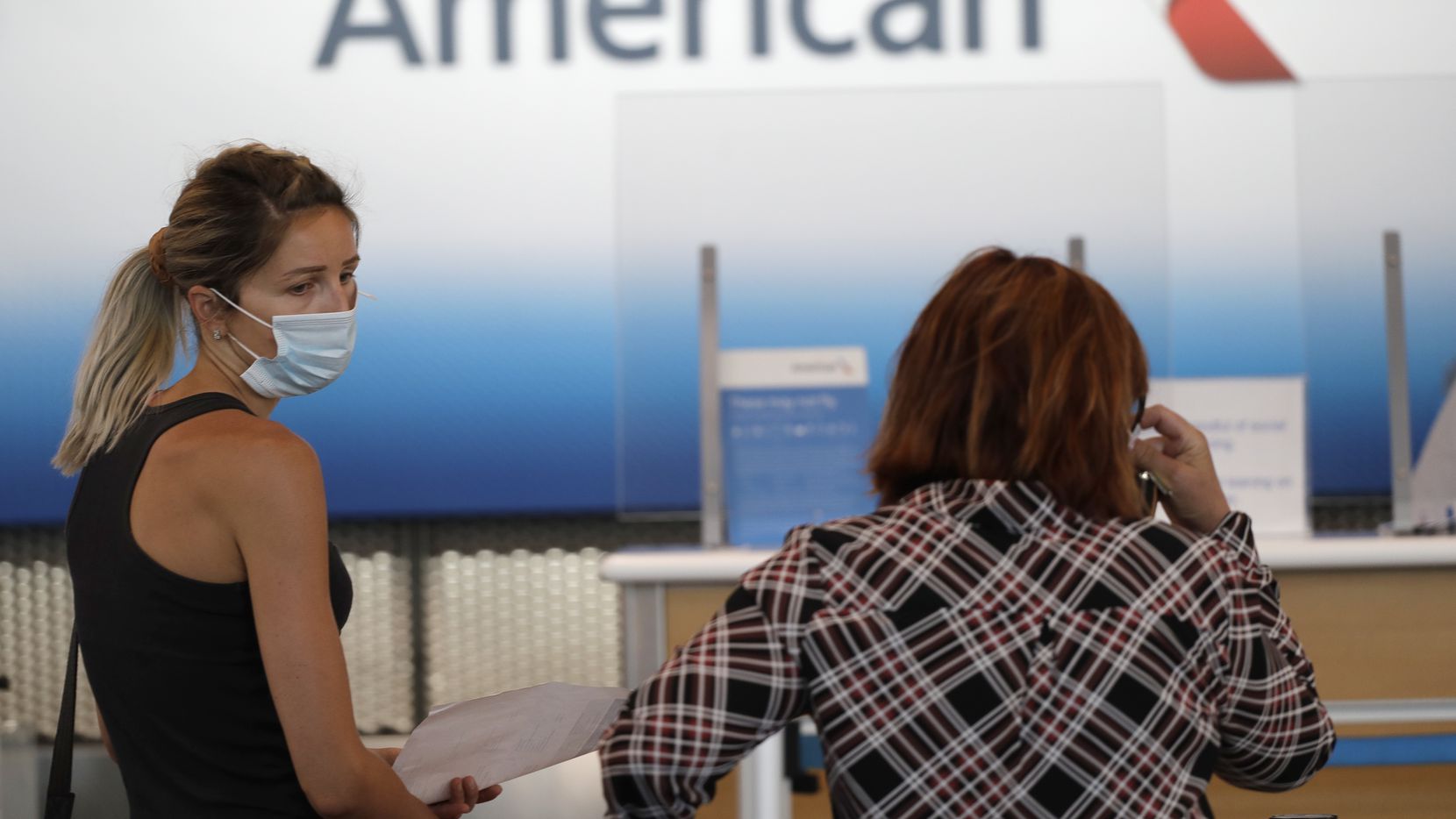 Travelers wear masks as they wait at the American Airlines ticket counter at O'Hare...