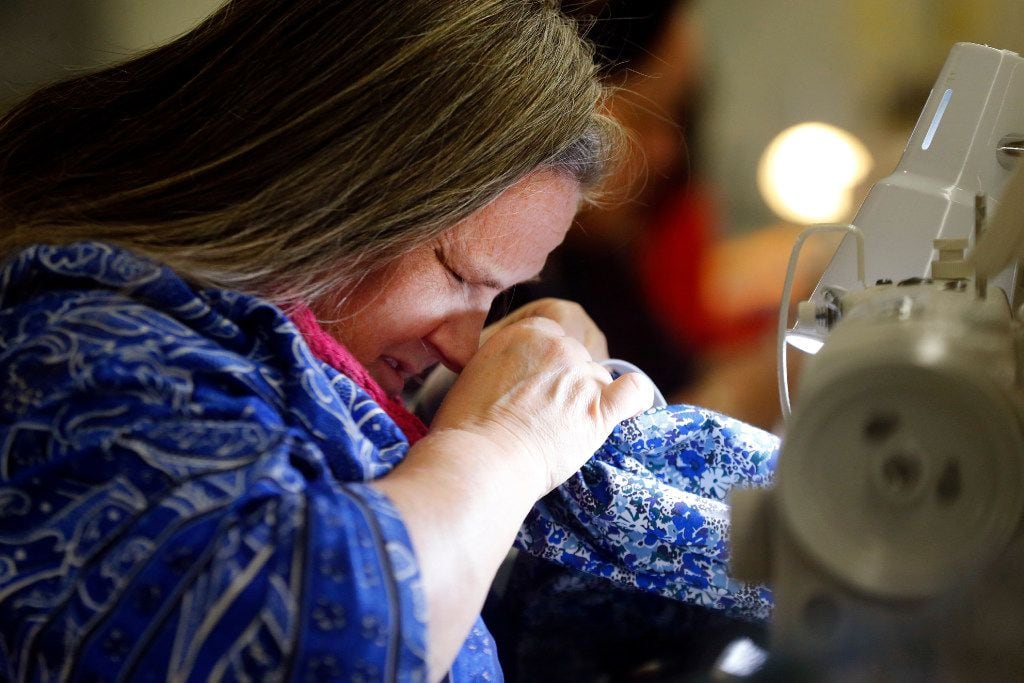 Visually impaired worker Elaina Tillinghast of Dallas draws a Kloe top closer so she can see the progress made on one of Dallas designer Tish Cox's fashions. (Tom Fox/The Dallas Morning News)