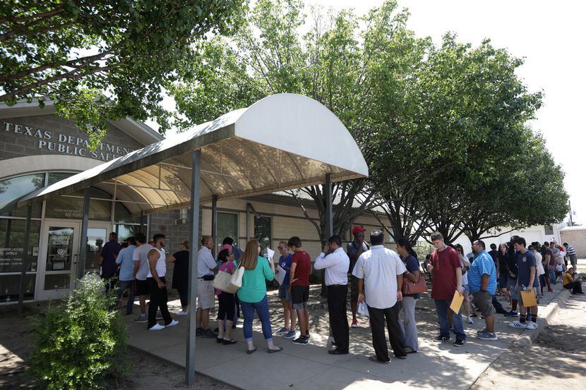 Decenas de personas hacen fila en las afueras de un centro de procesamiento de licencias en...