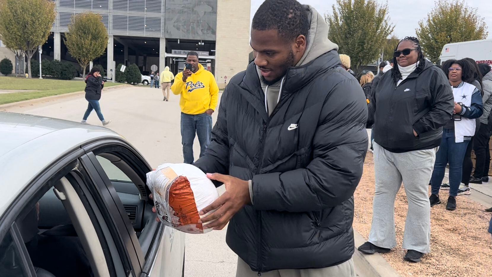 Cowboys linebacker Micah Parsons hands a turkey to a local family while his mother Sherese...