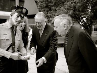 Sculptor Seward Johnson, far right, observes one of his sculptures of a police officer,...
