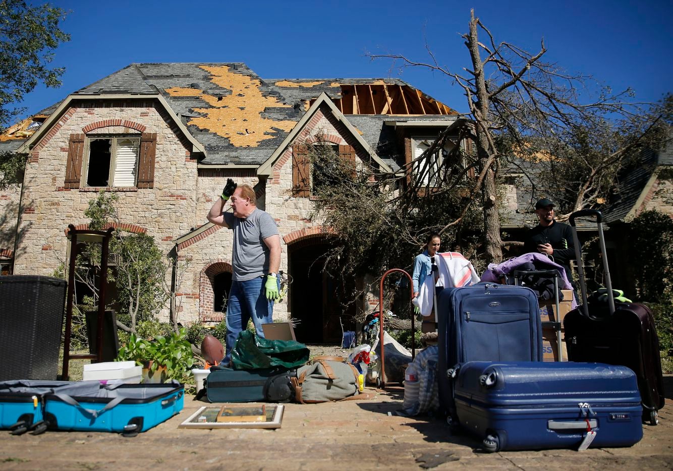 Ken Foster (center) wipes his brow while helping a friend clear some belongings from her...