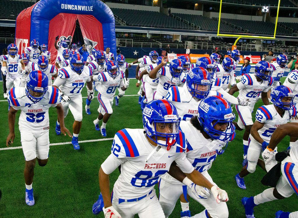 The Duncanville varsity football team emerges from an inflatable arch at the beginning of...