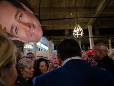 A supporter raises a cutout of Senator Ted Cruz's head as he signs souvenirs following his...