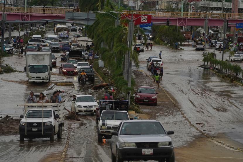 Autos cruzan una avenida anegada tras el paso del huracán Otis por Acapulco, México, el 25...