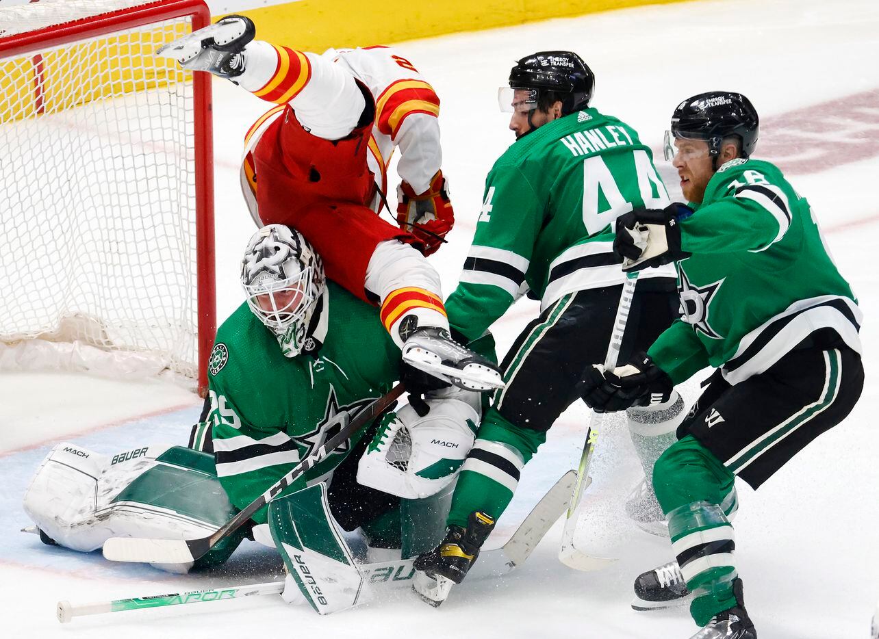 Dallas Stars goaltender Jake Oettinger (29) flips Calgary Flames center Blake Coleman (20)...