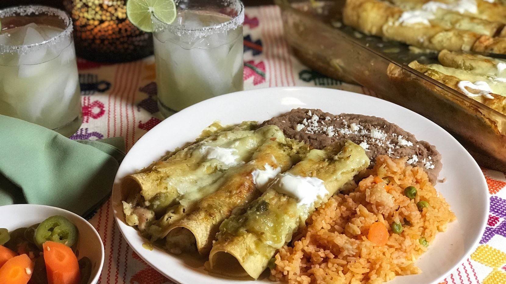A plate of enchiladas verdes, Mexican rice and refried beans