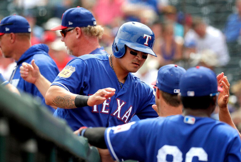 Texas Rangers' Shin-Soo Choo greets teammates after scoring on a base hit by James Loney...