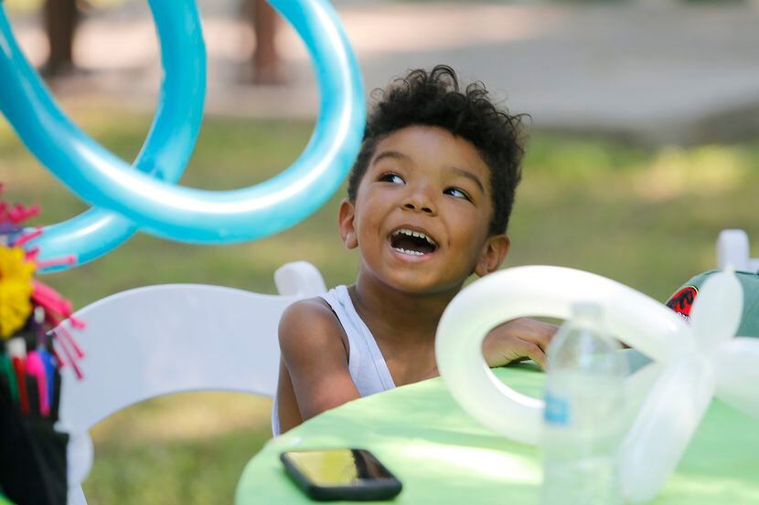 Asher Coleman, 3, waits with anticipation for his balloon creation as For Oak Cliff held a...