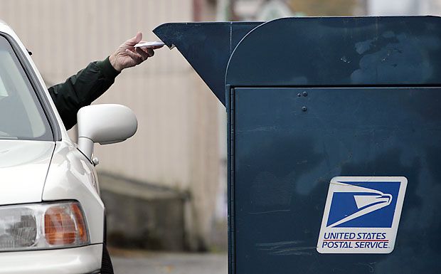 File photo of a customer dropping mail into a mailbox.