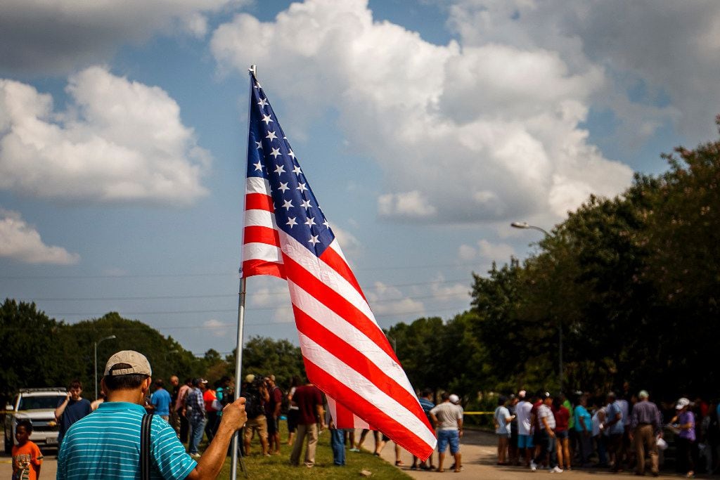 A resident of the Cinco Ranch Canyon Gate subdivision holds the American Flag during a...