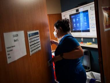 Nurse resident Jaime Luna peeks through a doorway into a patient room in the COVID-19 unit.