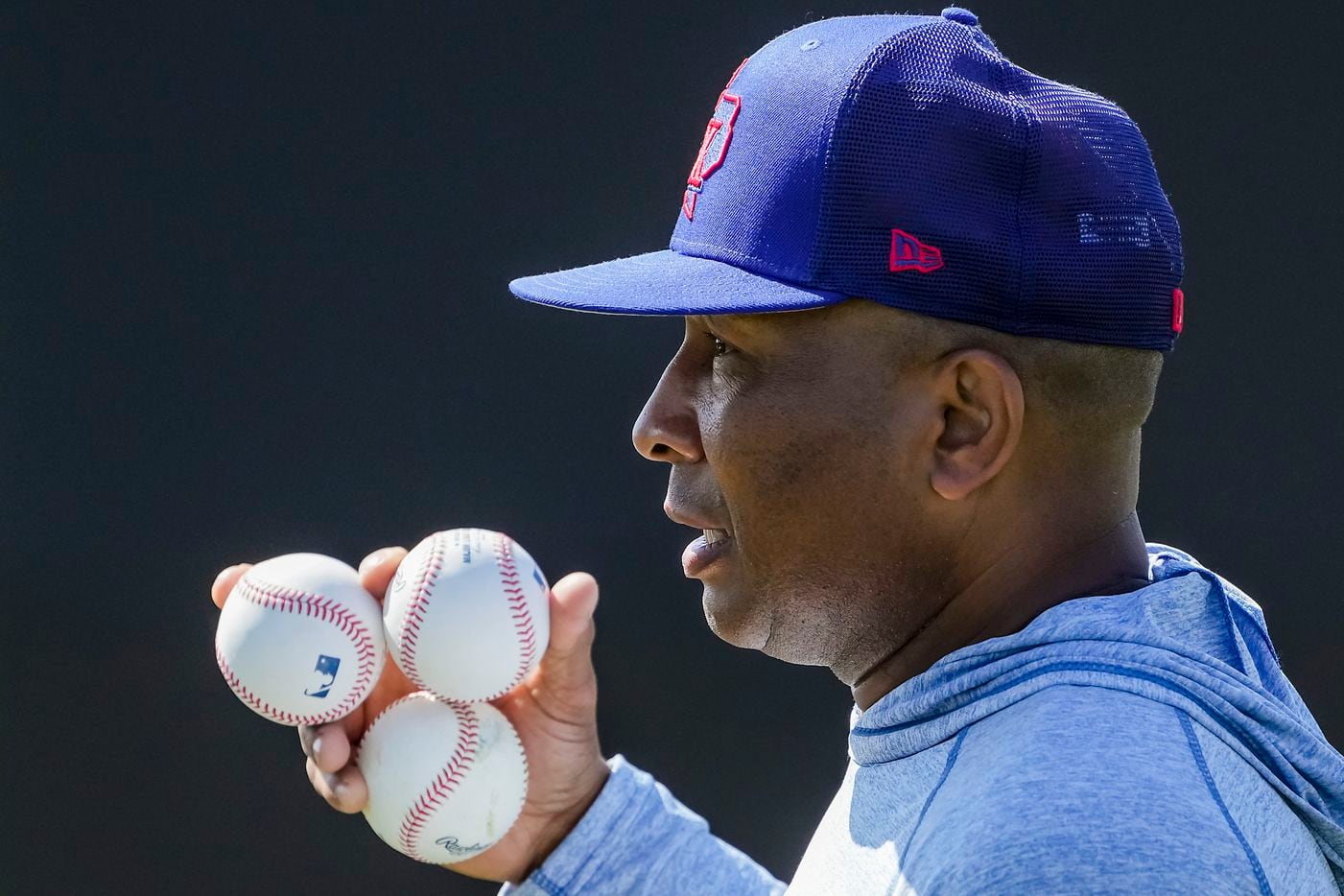 Texas Rangers third base coach Tony Beasley carries a handful of baseballs during a spring...