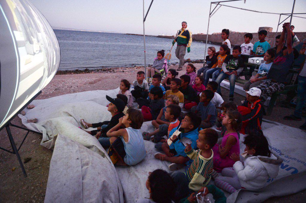 Refugee children watched a movie at an island camp in Greece this week. (Louisa...