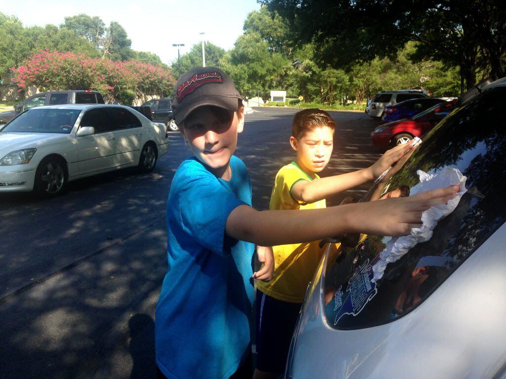 Cousins Will Harris, 11, and Nate Lazaro, 10, wash a car window before applying blue tape in...
